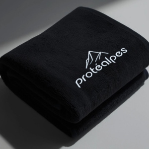 Black cloth towel with Protéalpes logo, representing our commitment to sports nutrition without additives or sweeteners.