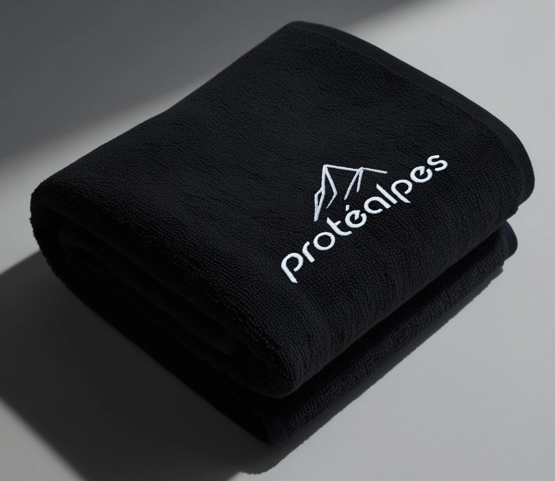 Black cloth towel with Protéalpes logo, representing our commitment to sports nutrition without additives or sweeteners.