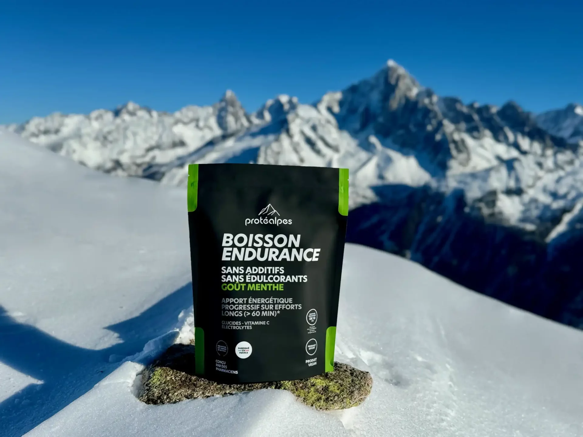 Bevanda Protéalpes senza additivi né dolcificanti, sulla neve, montagna sullo sfondo, alimentazione sportiva naturale.