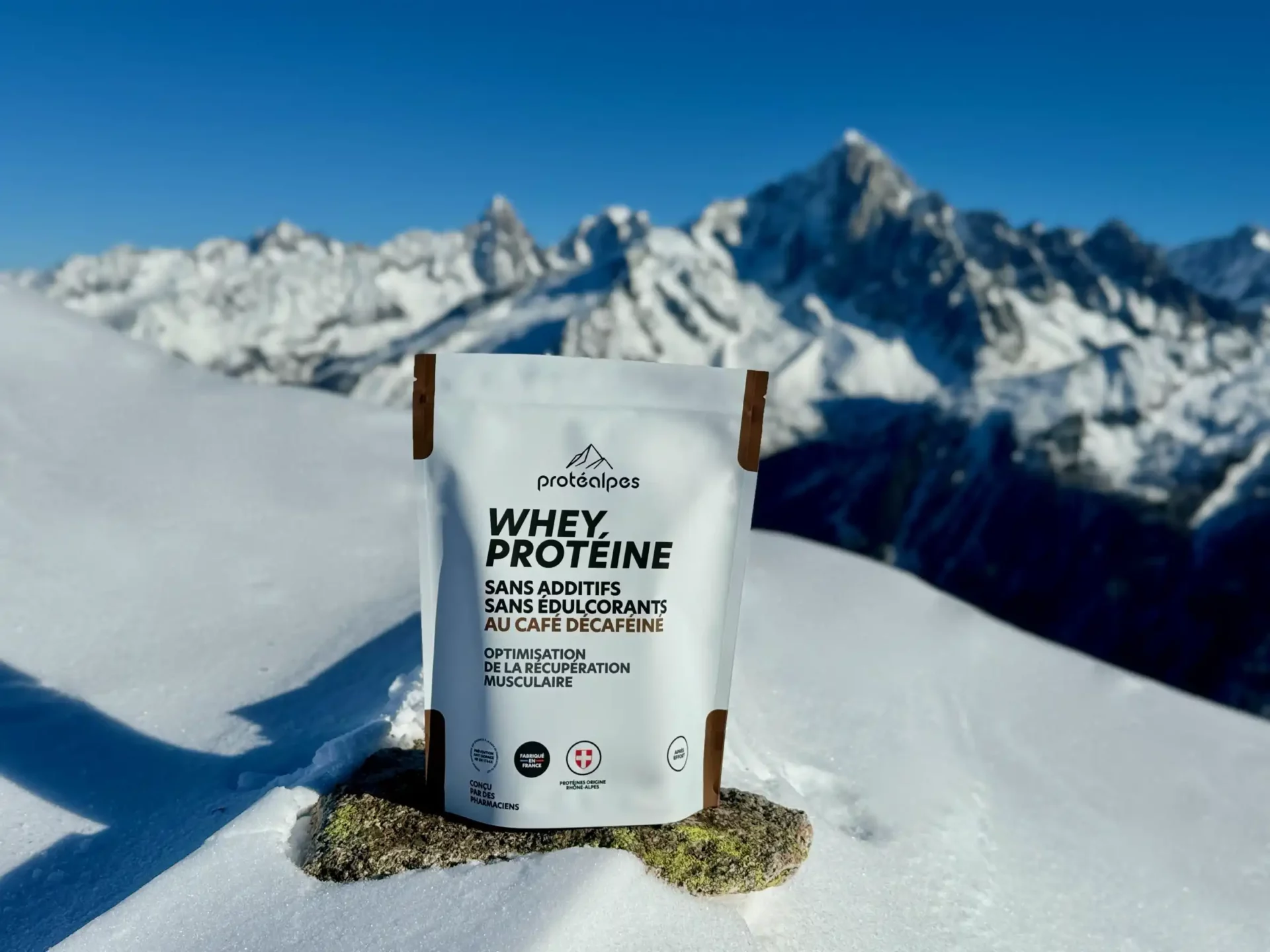 Pack de Whey Protéine Protéalpes sans additifs ni édulcorants, sur fond de montagnes enneigées, symbolisant pureté et qualité.