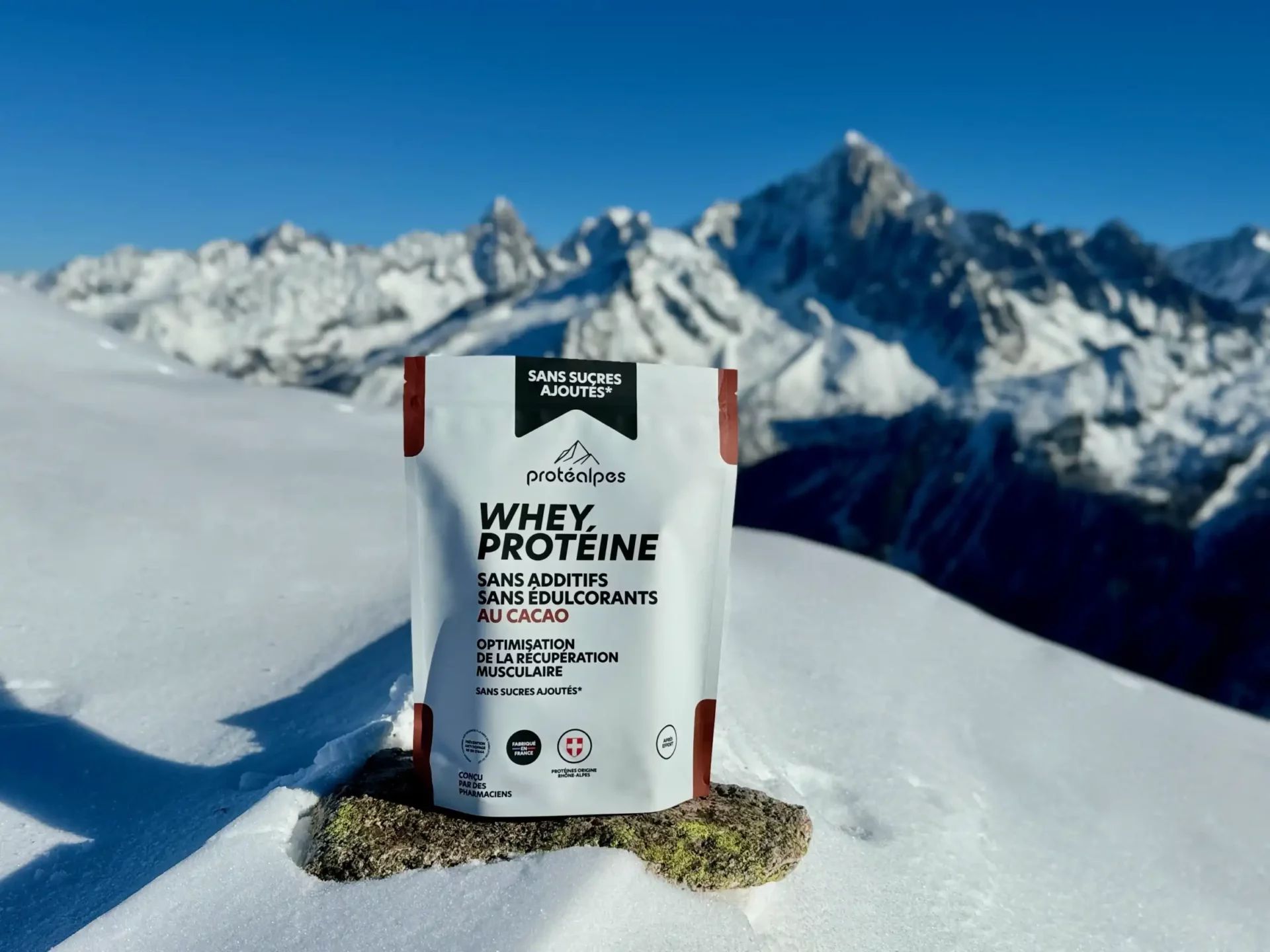 Whey protein Protéalpes with cocoa, no sweeteners or additives, in a snowy alpine landscape. Pure, natural nutrition.